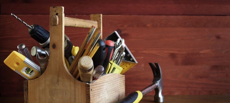 Wooden toolbox holding assorted hand tools on a wooden table.