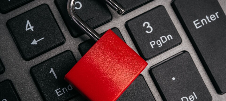 Red padlock lying across laptop keyboard keys.