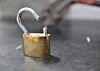 An open brass padlock with a bent shackle on a dark tabletop.