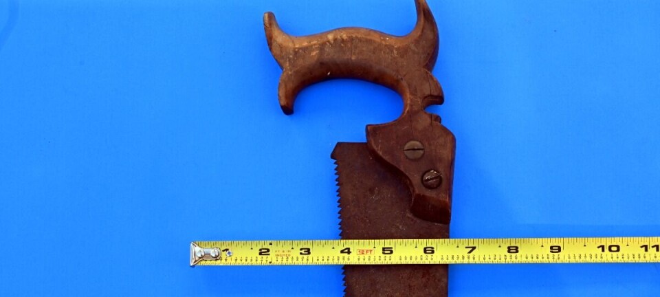 Rusty hand saw with two measuring tapes on a blue background.
