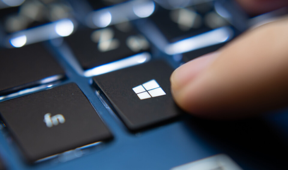 Close-up of a finger pressing the Windows key on a laptop keyboard.
